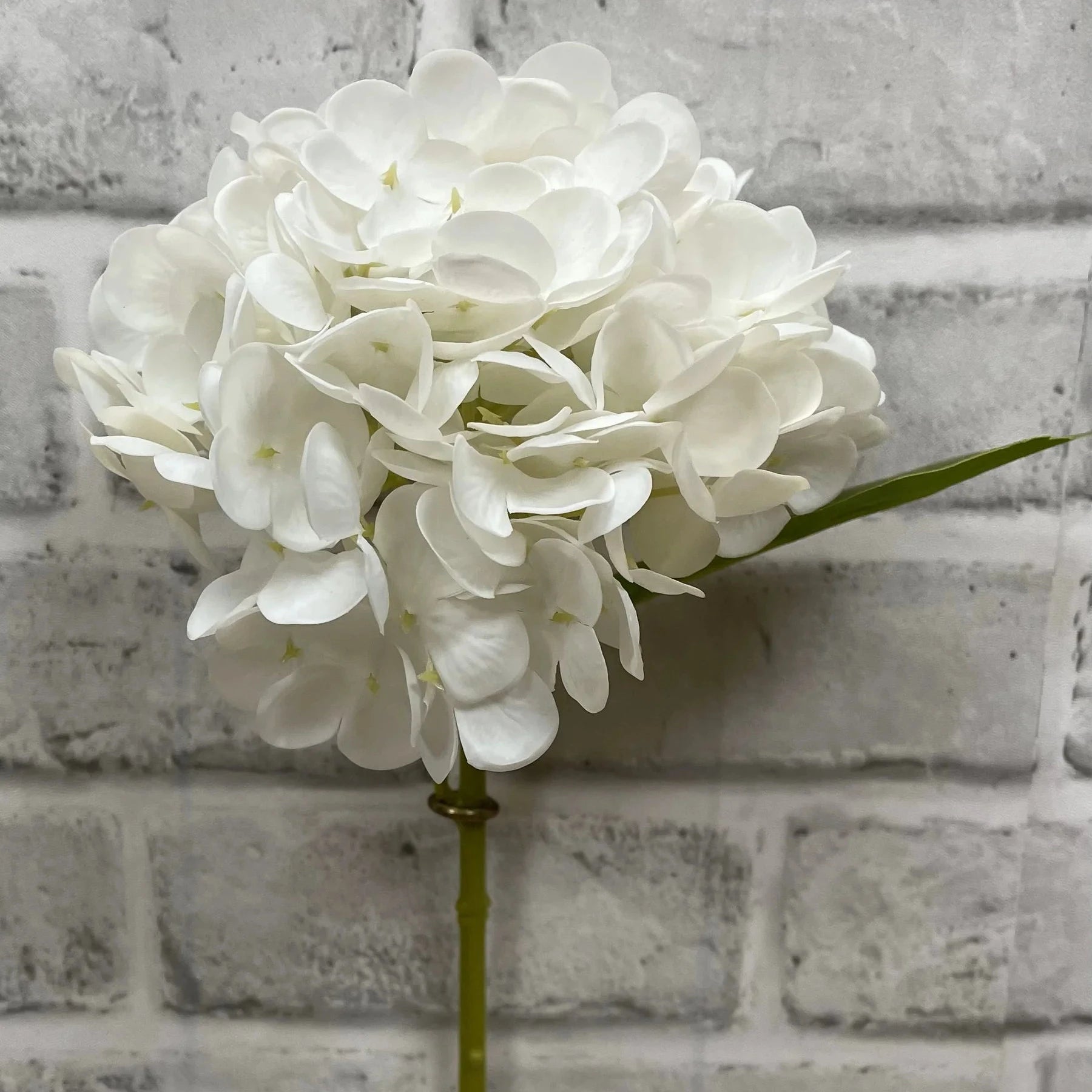 White artificial flower arrangement against a gray brick wall