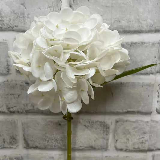 White artificial flower arrangement against a gray brick wall