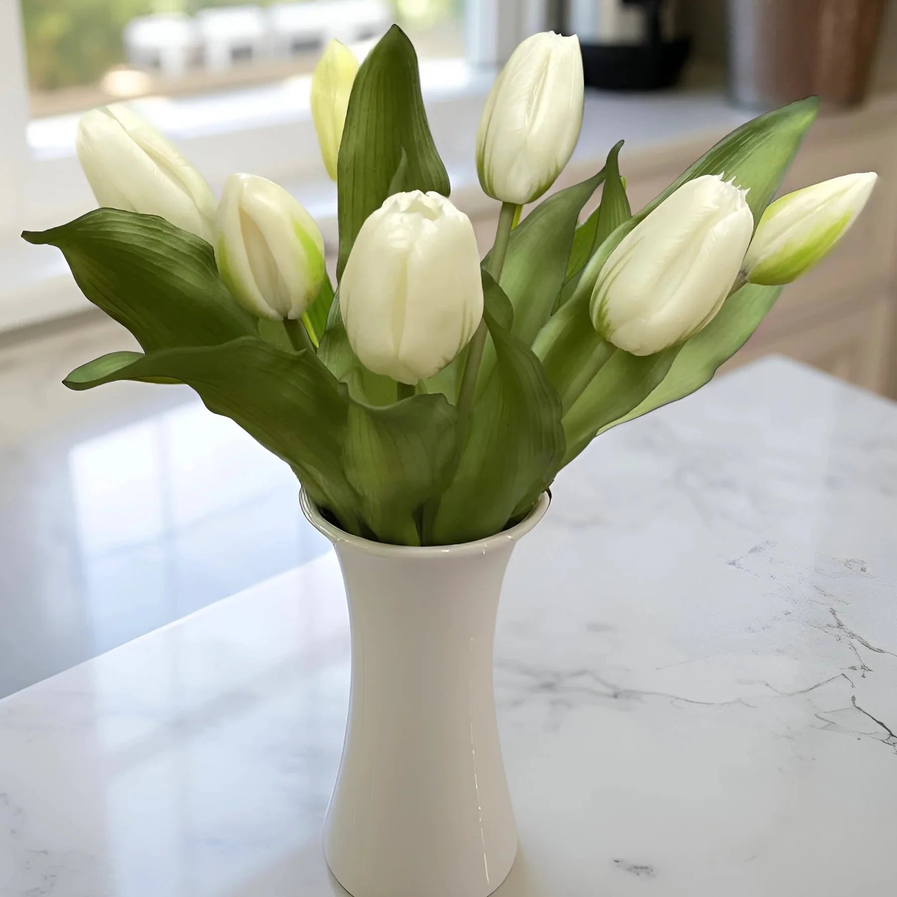 White tulips in a white vase on a marble countertop