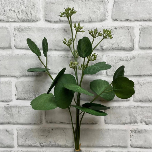 Artificial green plant against a white brick wall