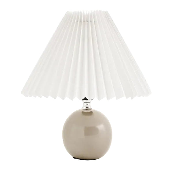 Table lamp with pleated white shade and beige base on a white background