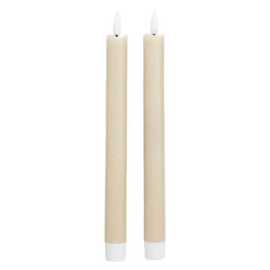 Two beige candles with white wicks on a white background