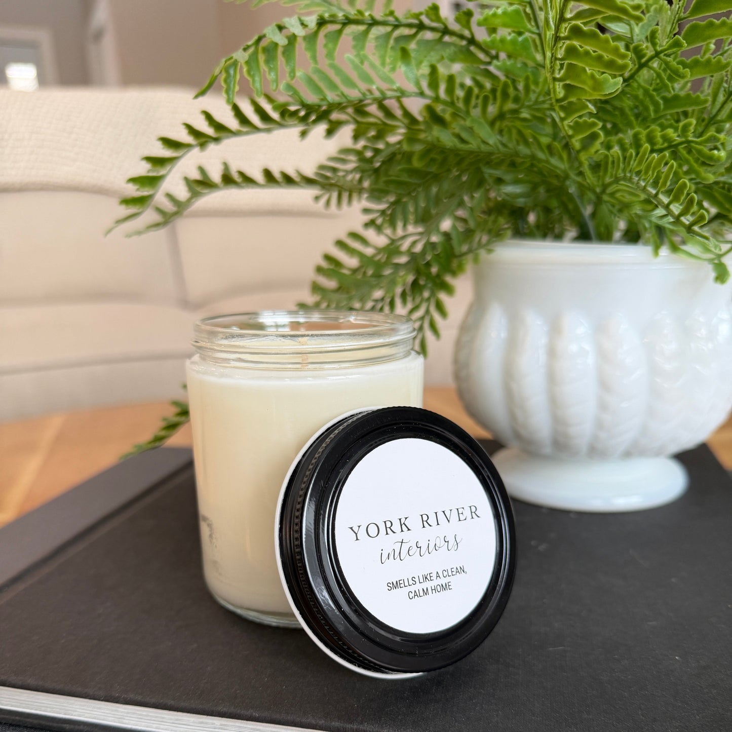 Jar of York River Candle on a coffee table with a plant in the background